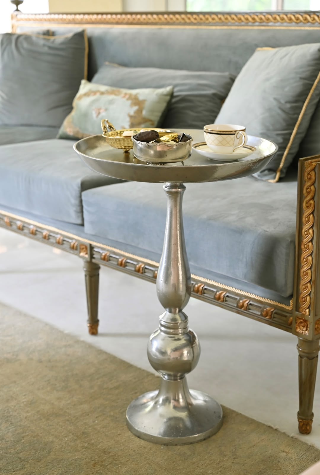 Silver-toned accent table with a round top and pedestal base